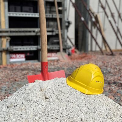 Sandhügel, mit Schaufel und Bauarbeiterhelm