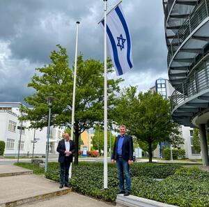 Bild vergrößern: Erster Kreisbeigeordneter Thorsten Schorr und Landrat Ulrich Krebs stehen vor der gehissten israelischen Flagge vor dem Landratsamt.